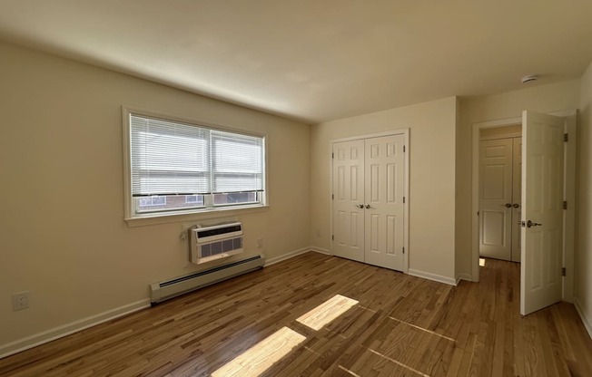 A room with wooden floors and a window with blinds.