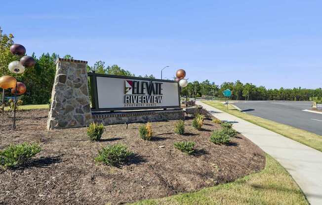 A sign for Heviq Riverview in front of a road.