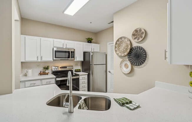 A kitchen with a sink, refrigerator, and microwave.