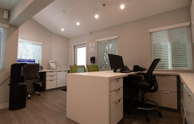 A white reception desk with a black chair in front of it.
