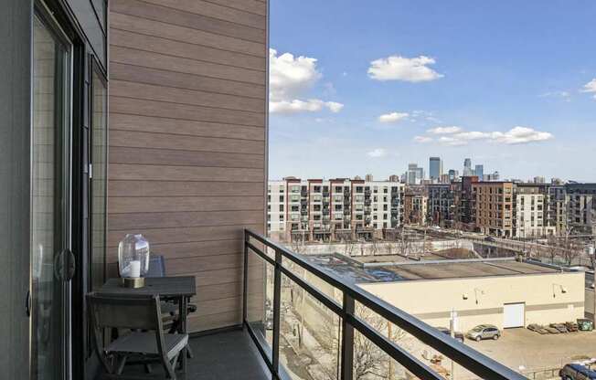 A balcony with a table and chairs overlooking a city skyline.