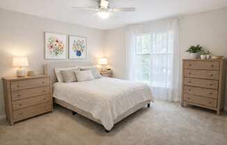 A bedroom with a bed, two nightstands, and a ceiling fan.
