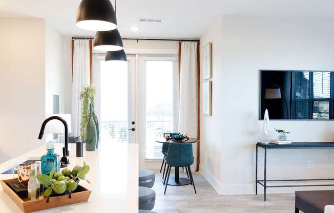 A modern kitchen with a black pendant light and a wooden tray with greenery on the counter.