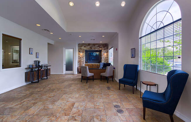 A living room with a stone floor and a large arched window.
