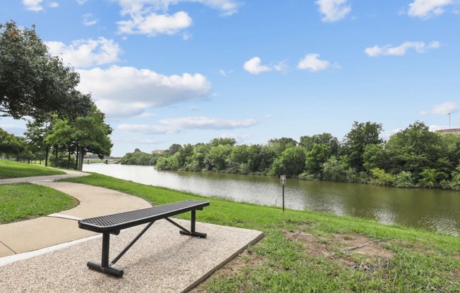 a bench sitting next to a river at Jefferson Creek in Irving, TX