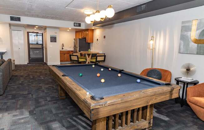 A pool table in a room with a couch and a fan.