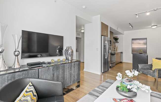 a living room with a large tv and a kitchen in the background