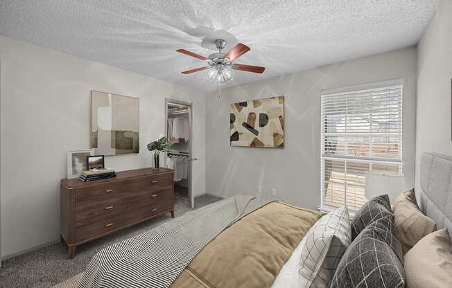 A bedroom with a bed, dresser, and window.