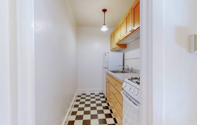 A Cozy Kitchen with Wood Cabinets and Black and White Checkered Flooring at The PArk Apartments in Minneapolis, MN