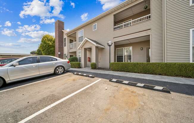 an empty parking lot in front of an apartment building with a car parked