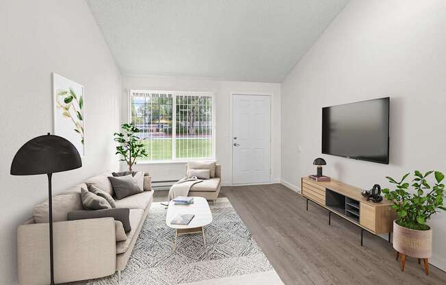 A living room with a grey couch, a black floor lamp, a white door, a grey rug, a wooden coffee table, a flat screen TV, and a plant.