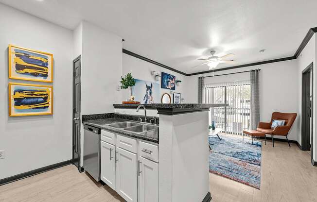 A kitchen with white cabinets and a black countertop.