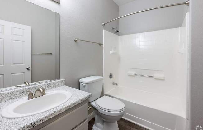 A white bathroom with a toilet, sink, and bathtub.