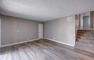A room with wooden flooring and a staircase.