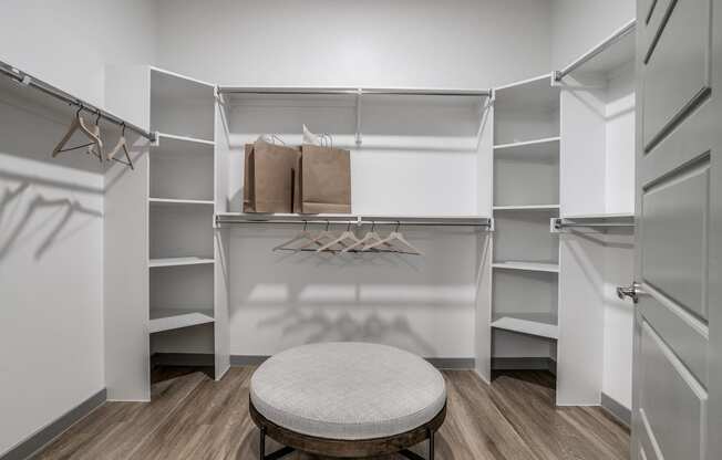 a walk in closet with a round stool in the middle