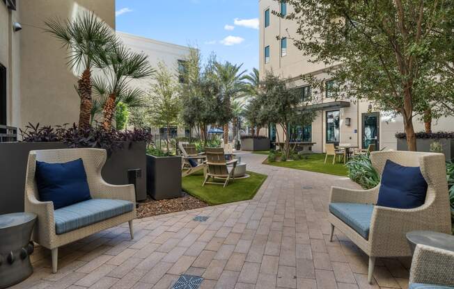 a courtyard with chairs and tables and a building in the background