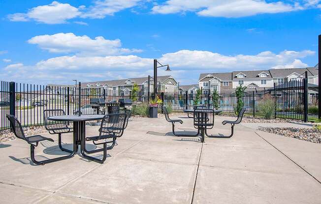 A concrete patio with grills, tables and chairs at Strathmore Apartment Homes, West Des Moines, IA