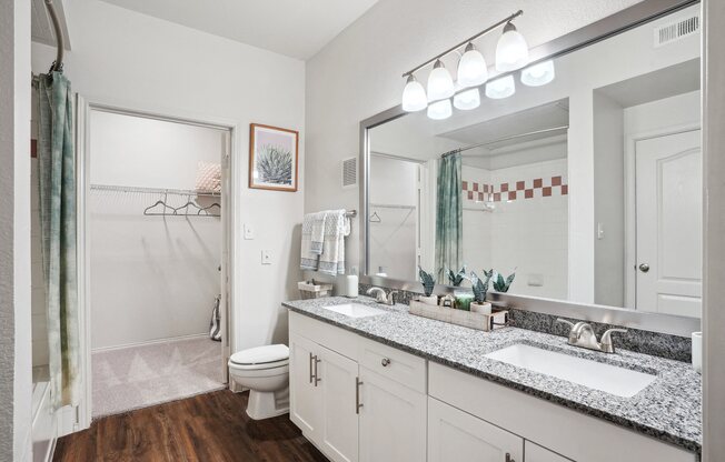 a bathroom with a large mirror and a sink and a toilet at La Ventura Apartments, Plano, Texas