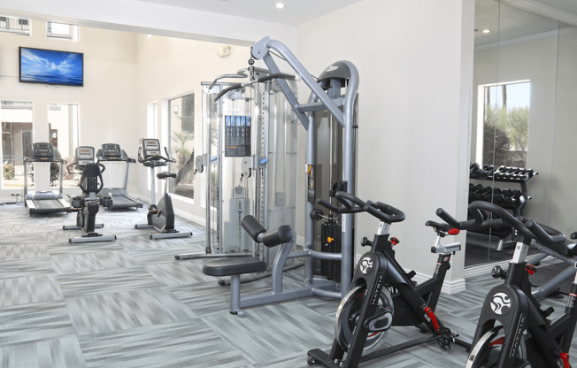 A gym with a variety of exercise equipment including treadmills, stationary bikes, and weight machines.