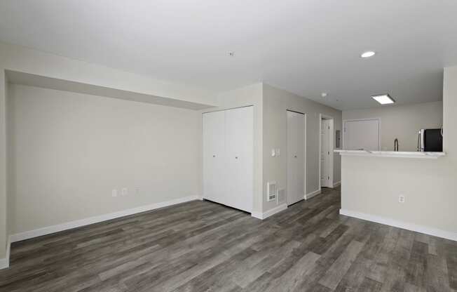 Interior View of a Spacious Living Room with Dark Hardwood Flooring and White Walls at Excalibur Apartment Homes, WA 98004