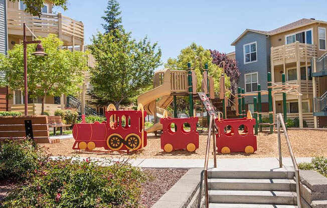 A playground with a red train and a slide.