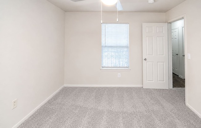 A room with a ceiling fan and a window with blinds.
