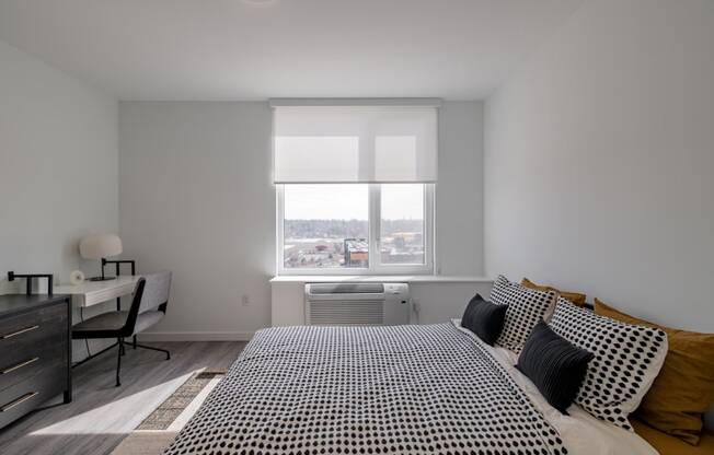 a bedroom with a bed and a desk and a window