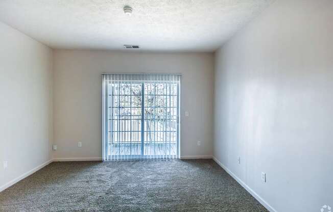 A room with a carpeted floor and a metal gate in the door.