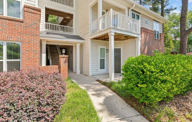 the pathway to the front entrance of an apartment building with a porch