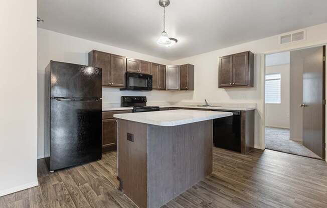 A kitchen with a black refrigerator, microwave, and stove top oven.