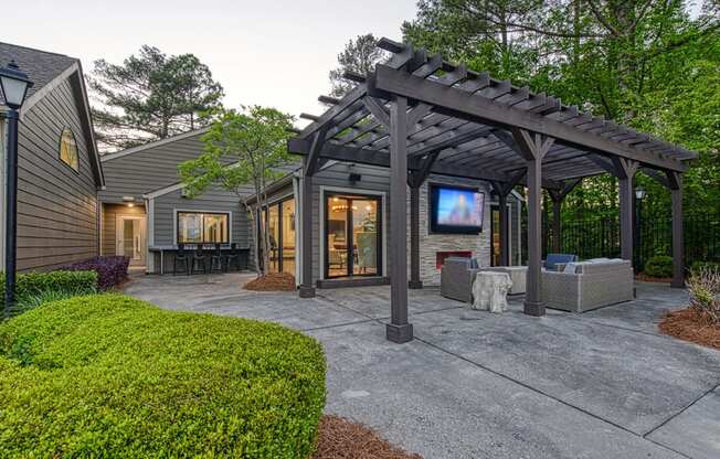 Wynnwood Vinings resident poolside lounge patio with glass entrance door and a pergola and TV with couches