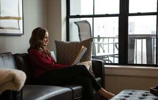 A woman in a red sweater is sitting on a black leather couch at The Pearl, Fort Wayne, 46802