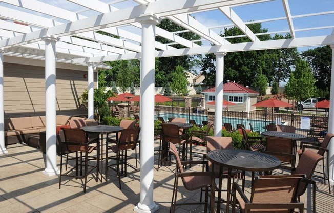 A patio with tables and chairs under a white pergola at Vermella Lyndhurst apartments, Lyndhurst 07071