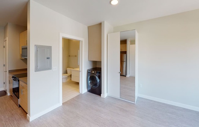 a living room and laundry room with a washing machine and a door to a bathroom at Canary Lofts, Iowa