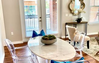 A dining room with hardwood-style flooring with access to a living room and near a double door entrance to a private balcony.