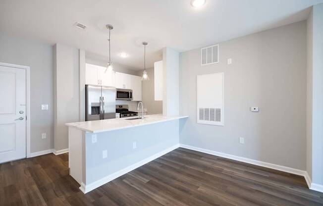 A kitchen with a white countertop and wooden flooring.