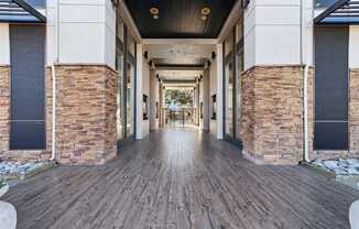 A long hallway with a wooden floor and stone pillars on either side.