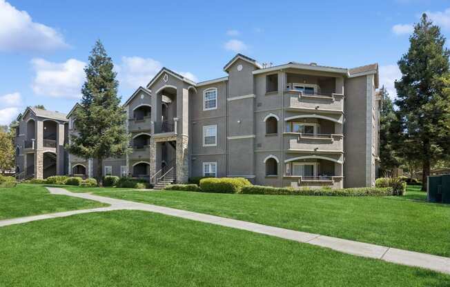 an apartment building with a green lawn and sidewalk