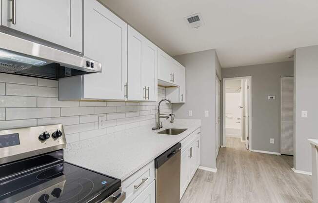 A kitchen with white cabinets and a black stove top.