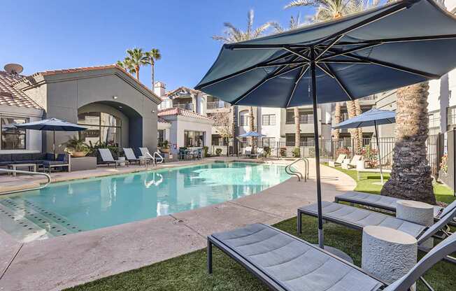 A poolside area with a large umbrella and lounge chairs.