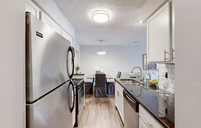 an open kitchen and dining room with stainless steel appliances and white cabinets