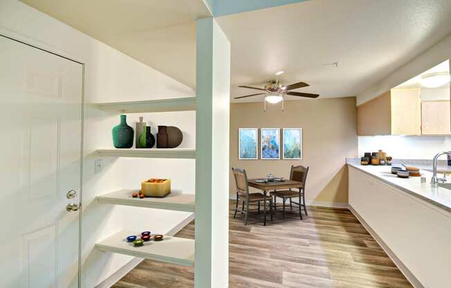 a dining room and kitchen with a table and a ceiling fan