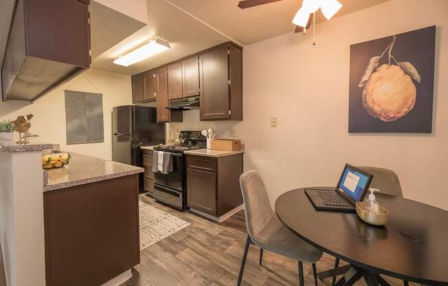 Model kitchen with a table and chairs and a laptop on it  at Pheasant Pointe Apartments, California, 95833