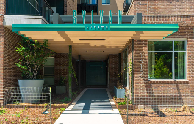 the red brick entrance to the property with a green awning at Sylvan Uptown, Denver, CO