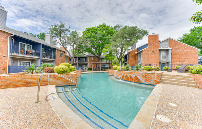 A small pool surrounded by a brick wall and steps leading to a house.