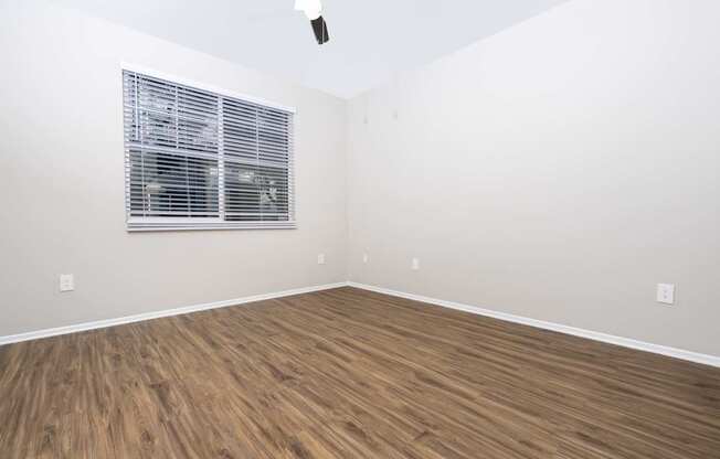 A room with a ceiling fan and wooden flooring.