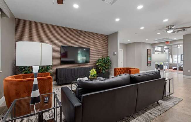 A modern living room with a black couch and a television on the wall.