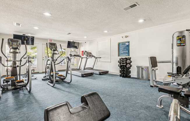 A gym with a variety of equipment including treadmills, stationary bikes, and weight machines.