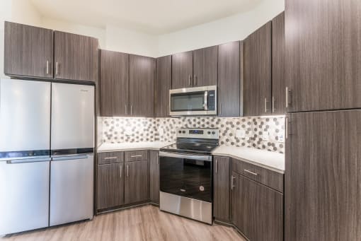 Kitchen with dark wood cabinets and white countertops at Residences at 3000 Bardin Road, Grand Prairie, TX, 75052