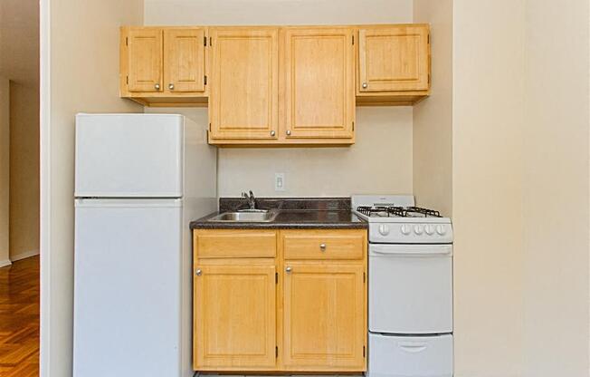 kitchen with light oak cabinetry, stove, refrigerator and sink at brunswick house apartments in dupont circle washington dc